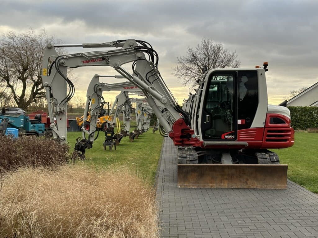 Row of construction excavators on grass